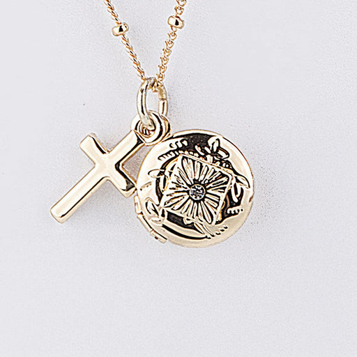 Gold necklace with a cross and circular pendant on a light gray background