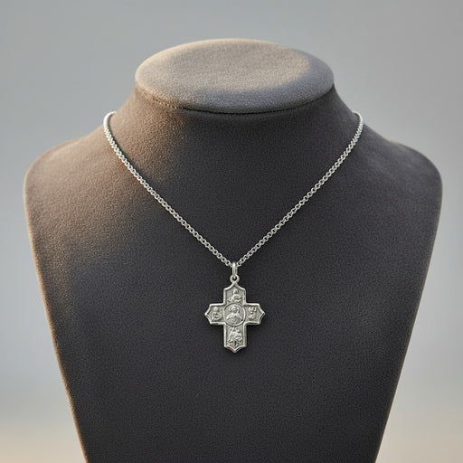 Silver cross pendant necklace on a mannequin bust with a gray background