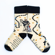 A pair of socks featuring a design with religious and mystical elements, including a figure of St. Dominic and symbols such as a torch and stars, on a white background.