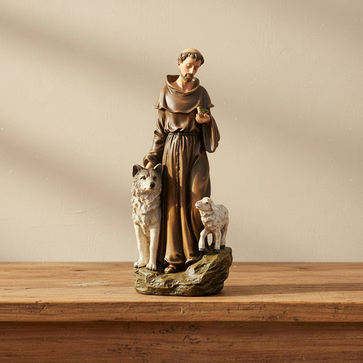 Statue of St. Francis of Assisi with a wolf and a lamb on a wooden surface