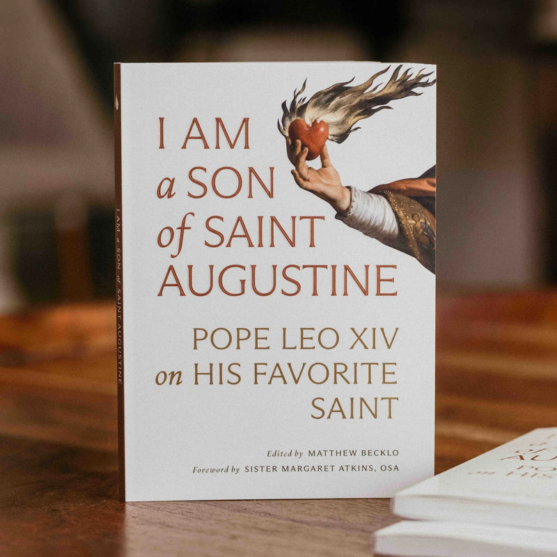A white book with an image of a hand holding a flaming heart and the text 'I Am a Son of Saint Augustine' on a wood table.