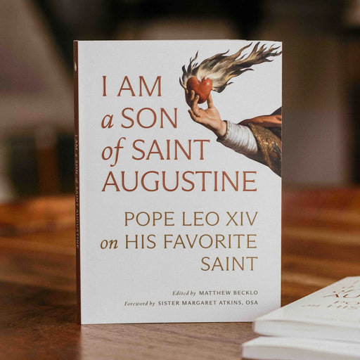 A white book with an image of a hand holding a flaming heart and the text 'I Am a Son of Saint Augustine' on a wood table.