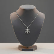 Silver necklace with an anchor pendant on a gray mannequin bust against a gray background