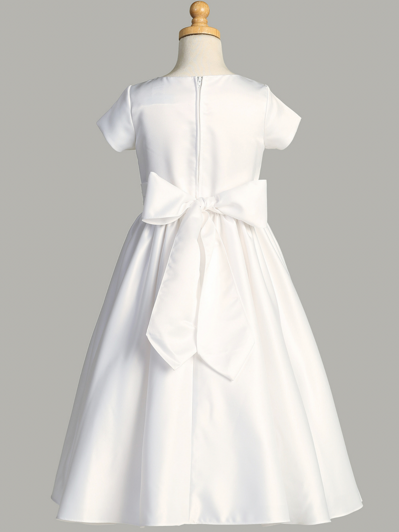 Rear view of a white First Communion dress with a ribbon-tied belt over a gray background.