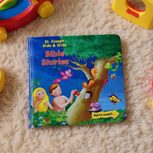 Children's book titled 'Bible Stories' by St. Joseph Hide & Slide on a carpeted floor with toys around.