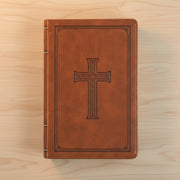 Brown leather Bible with a cross design on a wooden surface