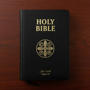 Black Bible with gold text and design on a wooden surface
