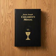 Black Saint Joseph Children's Missal with gold lettering on a wooden surface
