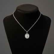 Silver necklace with a pendant on a black mannequin bust against a gray background