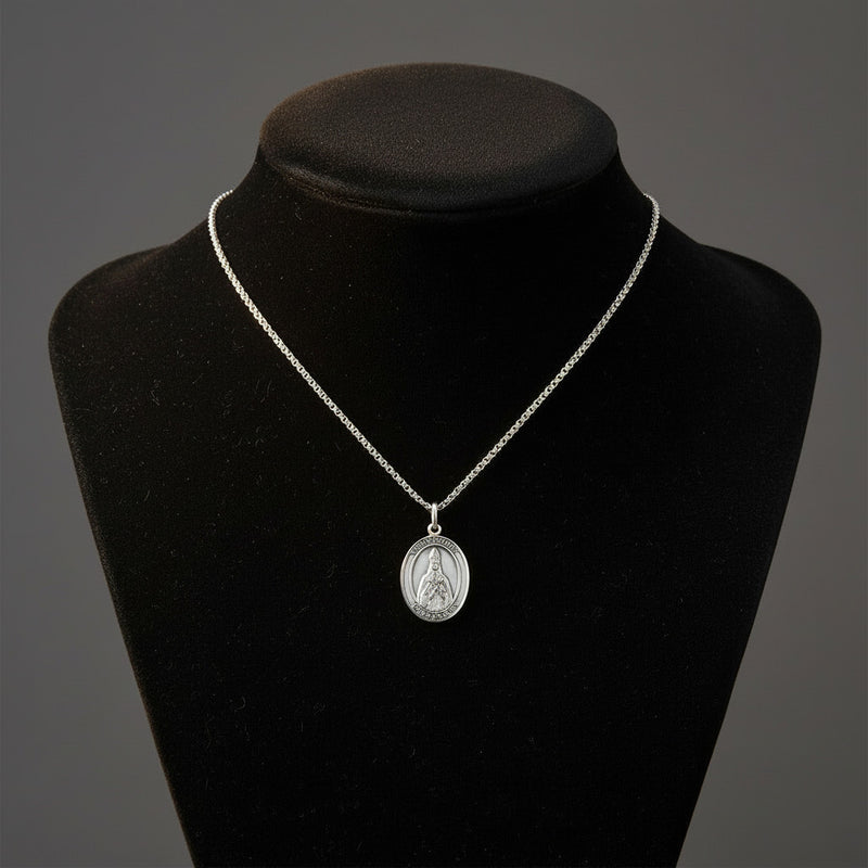 Silver necklace with a pendant on a black mannequin bust against a gray background