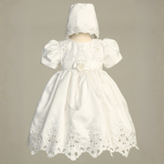 White lace dress with matching bonnet on a beige background