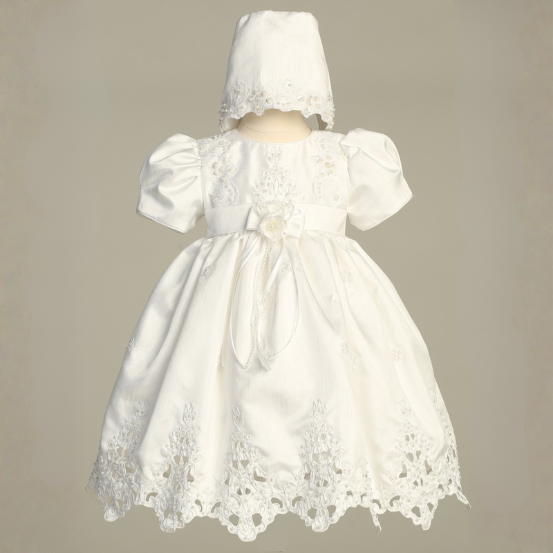 White lace dress with matching bonnet on a beige background