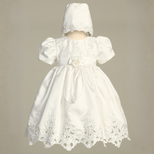 White lace dress with matching bonnet on a beige background