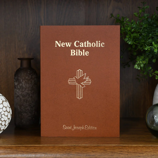 New Catholic Bible with cross symbol on a wooden surface with decorative items.