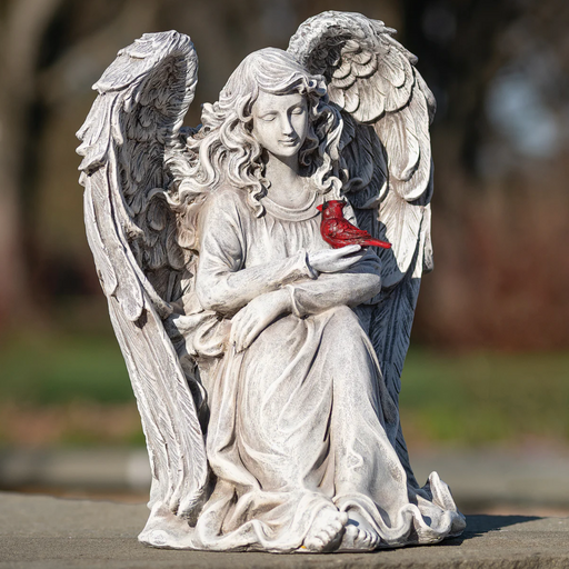 Statue of an angel holding a cardinal with a blurred natural background