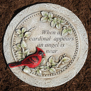 Decorative stone with a red cardinal and engraved text on a brown mulch background
