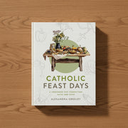 Book titled 'Catholic Feast Days' by Alexandra Greeley on a wooden surface