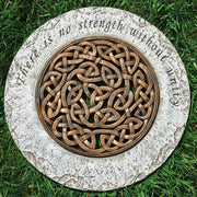 Decorative stone with Celtic knot design and engraved text on grass