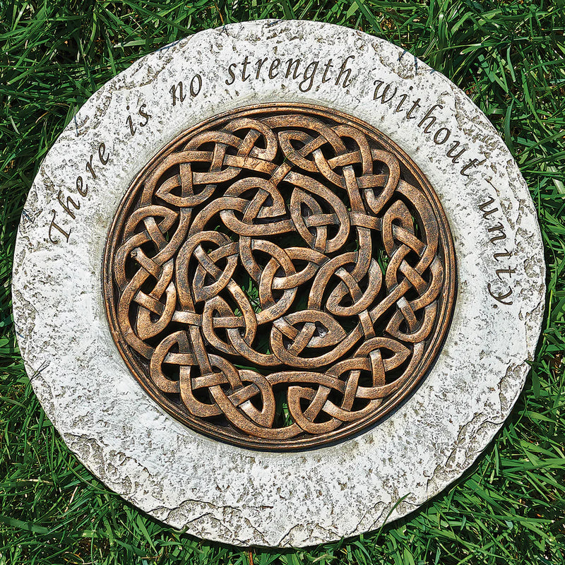 Decorative stone with Celtic knot design and engraved text on grass