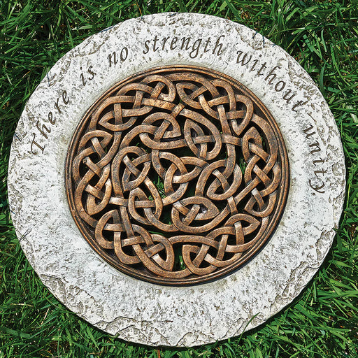 Decorative stone with Celtic knot design and engraved text on grass