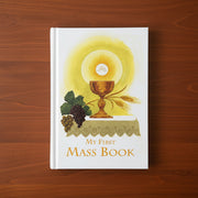 Book titled 'My First Mass Book' with religious illustration on a wooden surface