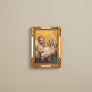 Framed artwork of the Holy Family with gold frame on beige wall