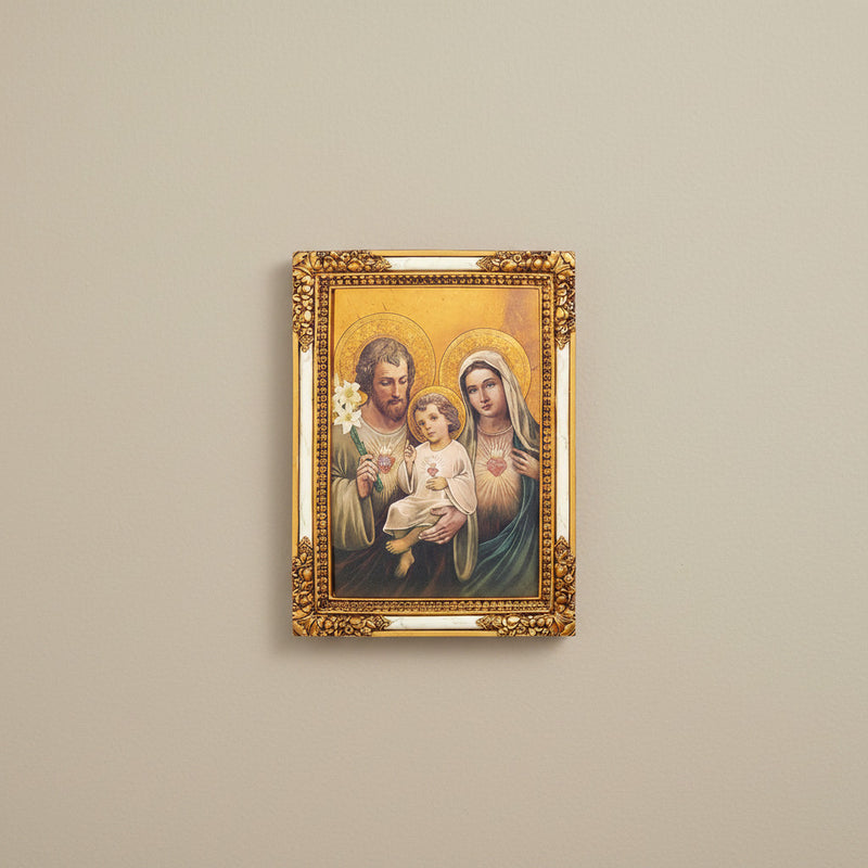 Framed artwork of the Holy Family with gold frame on beige wall