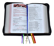 Open book with colorful bookmarks and a cross charm on a white background