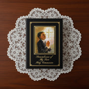 Book titled 'Remembrance of My First Holy Communion' with a praying child illustration on a lace doily.