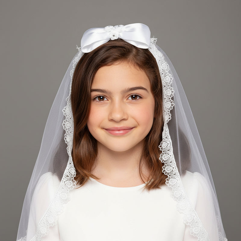 Young girl wearing a white Communion veil with a bow on a gray background