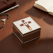 Hand opening a Confirmation jewelry box with a decorative cross emblem on a wooden surface.