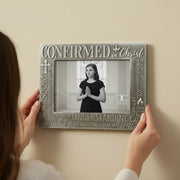 Person holding a decorative Confirmation photo frame with religious text and a black and white photo of a teenage girl.