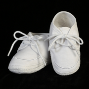 Pair of white baby shoes with laces on a black background