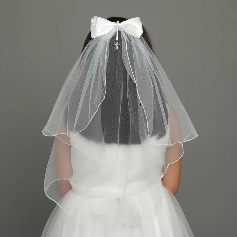 White First Communion veil and bow with a silver cross charm on a gray background