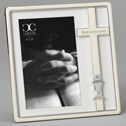 Ivory picture frame with a cross and 'First Communion' text, featuring a black and white photo of hands on a book.
