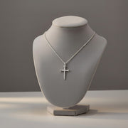 Silver cross necklace on a gray mannequin bust against a gray background