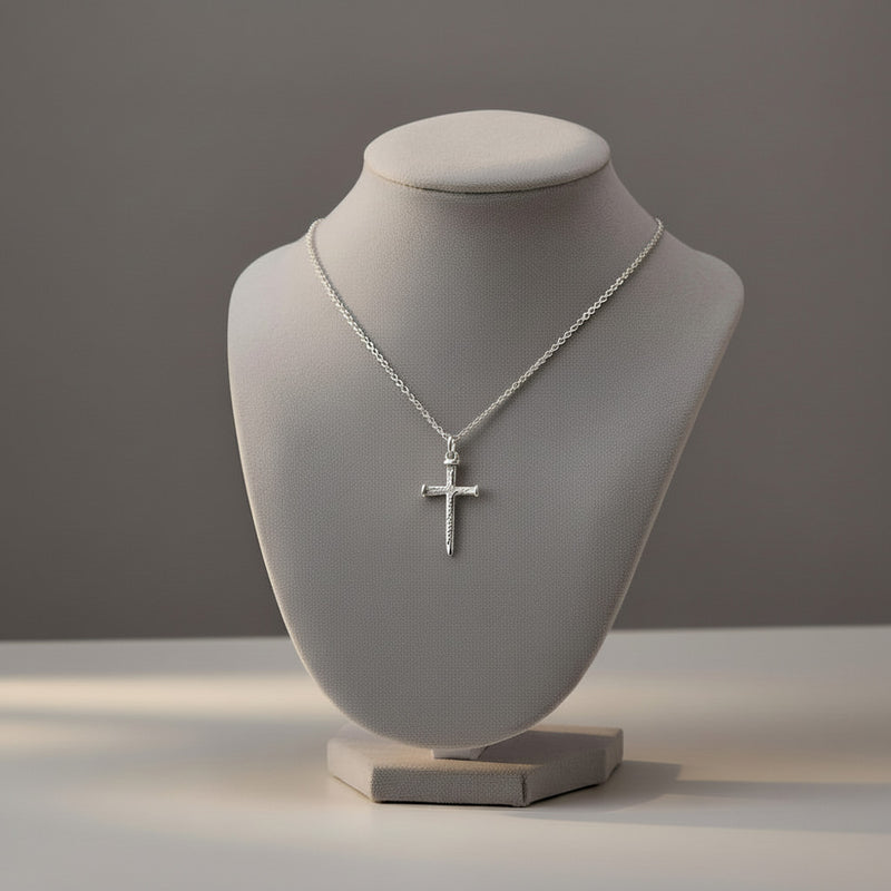 Silver cross necklace on a gray mannequin bust against a gray background
