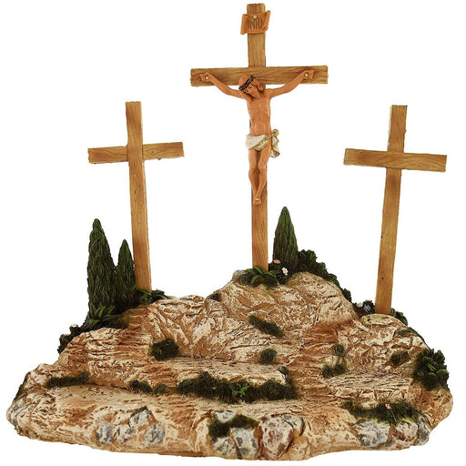 A 4-piece set of a crucifixion scene, featuring a wooden cross with a figure of Jesus Christ, two smaller crosses, and a backdrop with rocks and a green slope.