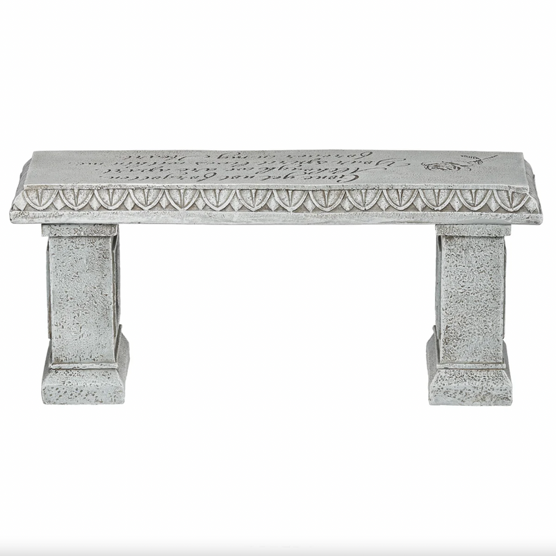 Decorative memorial stone bench with intricate carvings on a white background