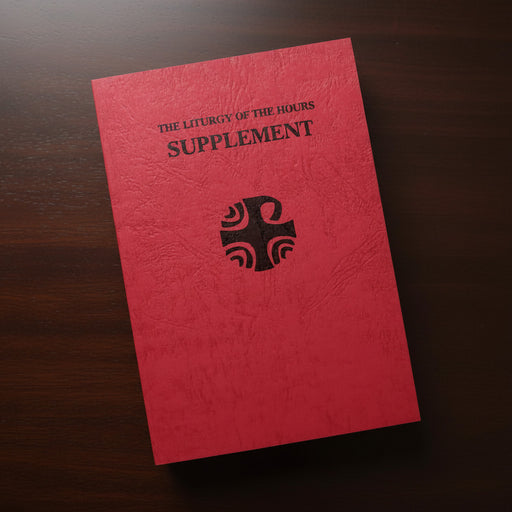 Red book titled 'The Liturgy of the Hours Supplement' with a black cross symbol on a wooden surface.