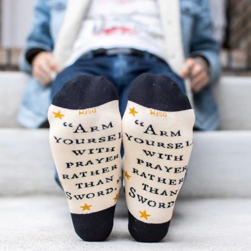 Person wearing crew socks with text 'Arm yourself with prayer rather than sword'