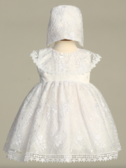 White lace baptism dress with matching bonnet on a neutral background