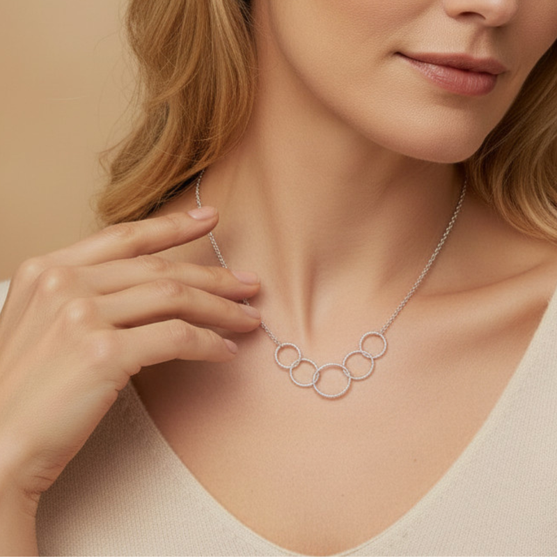 Woman wearing a silver necklace with interlocking rings against a beige background