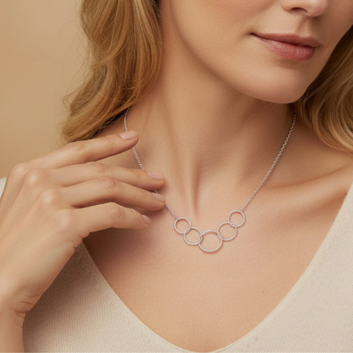 Woman wearing a silver necklace with interlocking rings against a beige background