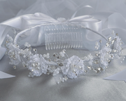 Studio photo of a white communion veil with corded flowers, pearls, and rhinestones, featuring a satin bow at the back.
