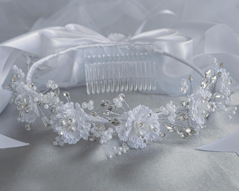Studio photo of a white communion veil with corded flowers, pearls, and rhinestones, featuring a satin bow at the back.