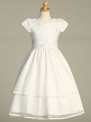 A white First Communion gown over a gray background.