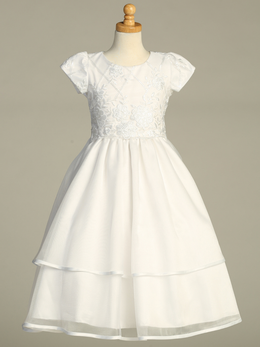 A white First Communion gown over a gray background.