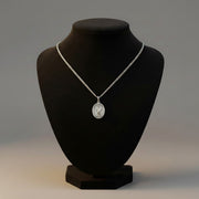 Silver necklace with a pendant on a black mannequin bust against a gray background