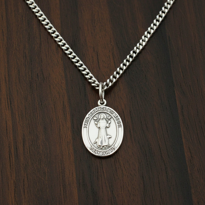 Silver medal of St. Francis of Assisi on a wood surface